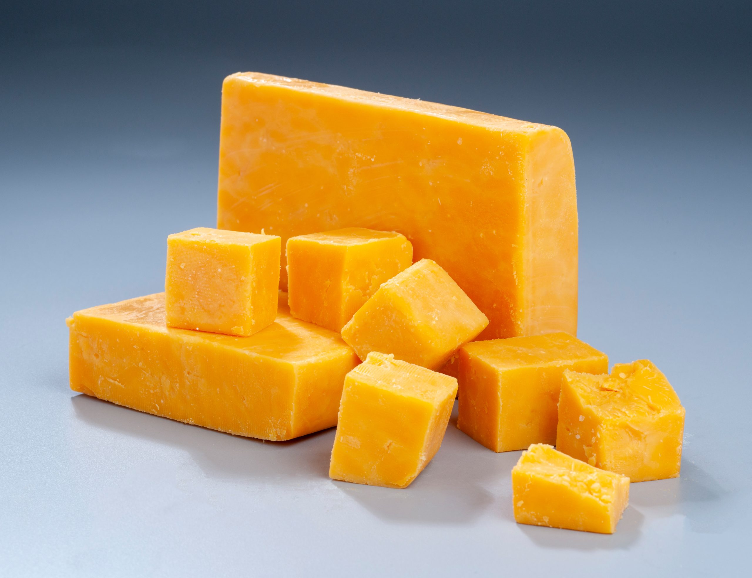 Red,Cheddar,Block,And,Cubes,On,Gradient,Background