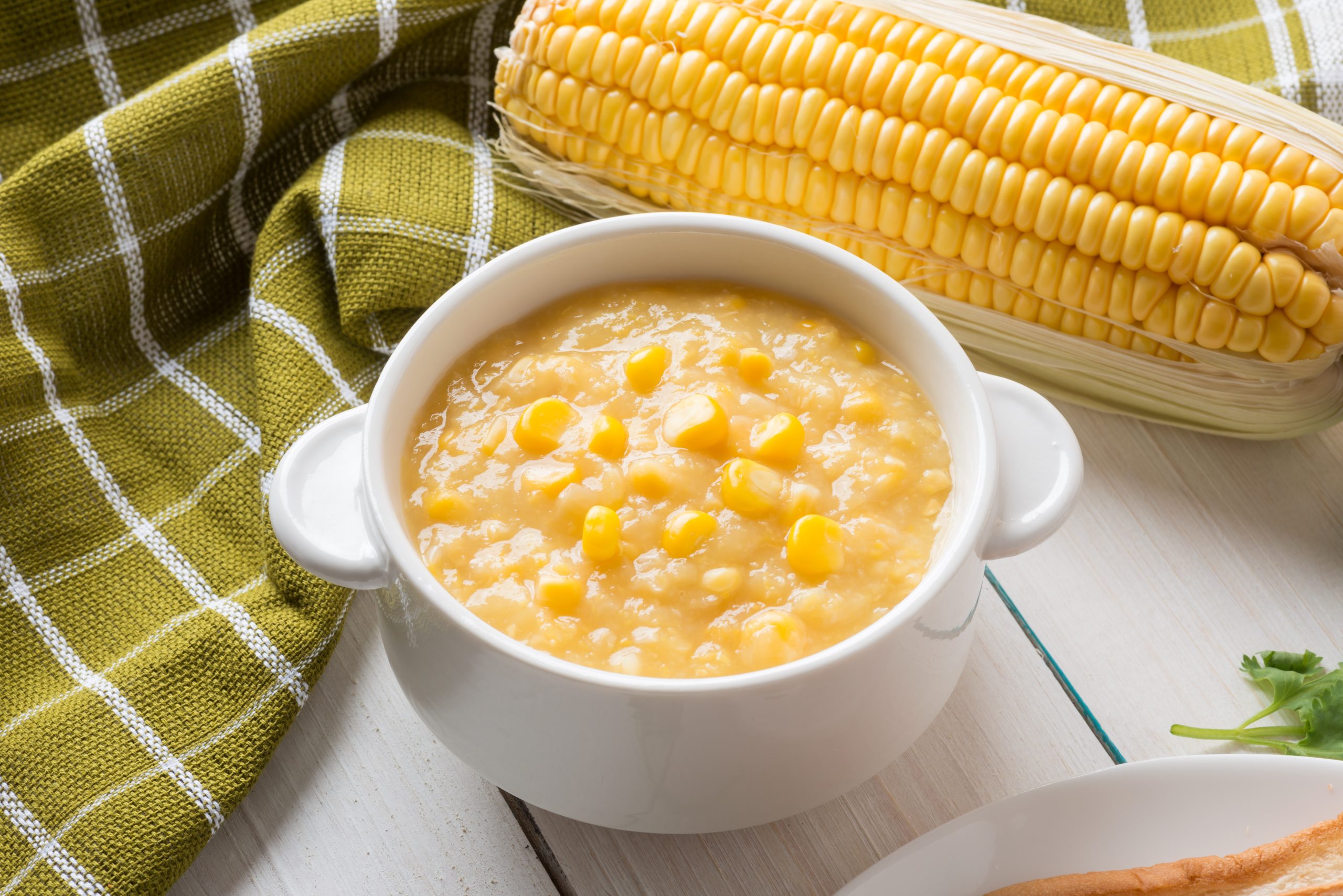 Corn,Soup,In,White,Bowl,And,Corn,On,White,Table.